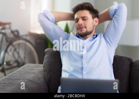 Uomo seduto sul divano con il computer portatile Foto Stock