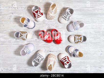 scarpe multicolore per bambini su fondo in legno non uniforme bianco-grigio Foto Stock