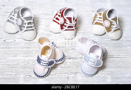 scarpe multicolore per bambini su fondo in legno non uniforme bianco-grigio Foto Stock