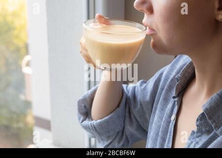 Giovane donna caucasica gustando una tazza di tè latte masala al mattino Foto Stock