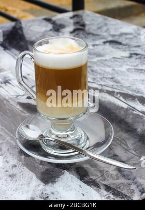 Caffè con latte in una tazza di vetro sul tavolo Foto Stock