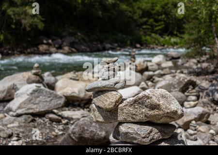 Armonia, equilibrio e semplicità. Una piramide di pietra sullo sfondo dell'acqua del fiume. Ciottoli di poise semplici, zen rock. Blu, vita. Foto Stock