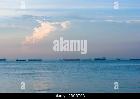 Navi da carico e petroliere ancorate in mare aperto lungo il rettilineo di Singapore, a Singapore Foto Stock