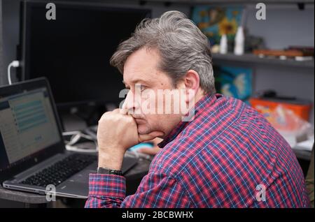 l'uomo dai capelli grigi lavora nella stanza dell'ufficio domestico Foto Stock