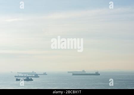 Navi da carico, petroliere e navi portarinfuse ancorate al tramonto lungo il rettilineo di Singapore Foto Stock