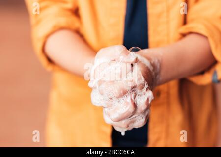 Bambino lavandosi le mani con sapone, primo piano, senza volto. Protezione antivirus Foto Stock