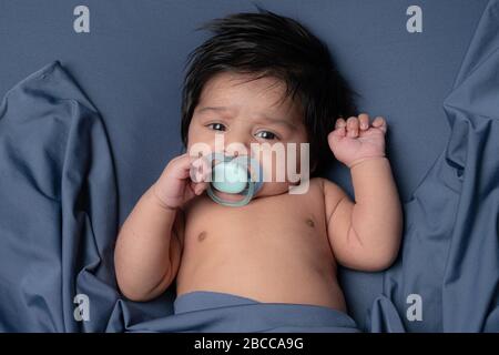 Foto ravvicinata di un piccolo adorabile bambino con i capelli neri con il succhietto Foto Stock