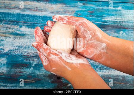 Qualcuno sta insaponando le loro mani con un pezzo di sapone da toletta su uno sfondo di legno. Primo piano. Il lavaggio delle mani è una prevenzione dell'infezione da COVID-19 Foto Stock