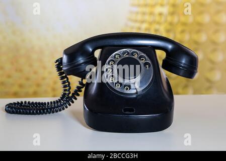 Un vecchio telefono con manopola rotante contro uno sfondo anni '70. Foto Stock