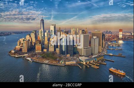 Vista aerea del quartiere finanziario di Lower Manhattan con grattacieli moderni e traghetto per Staten Island che arriva durante una splendida ora d'oro Foto Stock