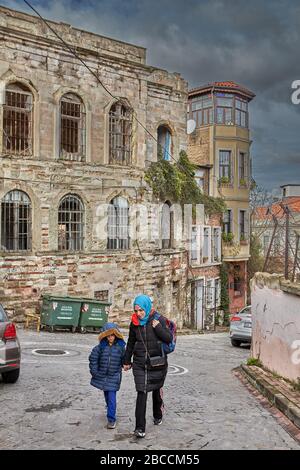 Istanbul, Turchia - 12 febbraio 2020: Balat è il tradizionale quartiere ebraico nel quartiere di Fatih. Una donna con un bambino, vestito in una vittoria calda Foto Stock