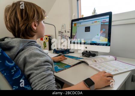 Giovane ragazzo, scuola elementare, home learning, fare scuola, imparare a distanza, aula virtuale, a casa al computer, effetti del cor Foto Stock