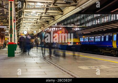 Lunga esposizione di passeggeri del treno sfocato che camminano lungo la piattaforma dopo aver lasciato un treno espresso di classe 43 delle East Midlands Railways di notte. Foto Stock