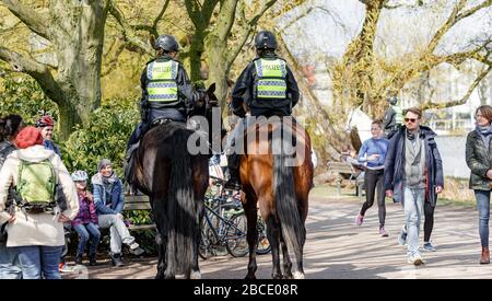 Amburgo, Germania. 04th Apr, 2020. I poliziotti montati fanno notare alle persone in un parco sull'Alster esterno che è vietato sedersi all'esterno su banchi come parte del divieto di contatto per contenere il coronavirus. Credito: Markus Scholz/dpa/Alamy Live News Foto Stock