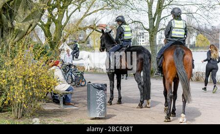 Amburgo, Germania. 04th Apr, 2020. I poliziotti montati fanno notare alle persone in un parco sull'Alster esterno che è vietato sedersi all'esterno su banchi come parte del divieto di contatto per contenere il coronavirus. Credito: Markus Scholz/dpa/Alamy Live News Foto Stock