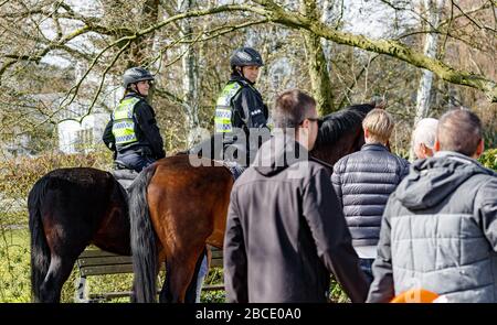 Amburgo, Germania. 04th Apr, 2020. I poliziotti montati fanno notare a persone in un parco sull'Alster esterno che, come parte del divieto di contatto per contenere il coronavirus, è vietato sedersi all'esterno su prati o panchine. Credito: Markus Scholz/dpa/Alamy Live News Foto Stock