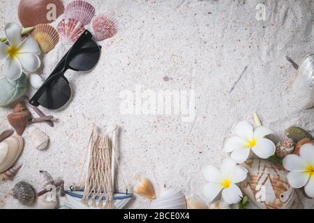 Occhiali da sole con conchiglie e fiori di plumeria su sfondo sabbia, spazio copia per testo di input e viaggio sulla stagione estiva concetto Foto Stock