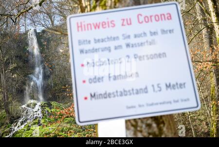 Bad Urach, Germania. 04th Apr, 2020. Davanti alle cascate di Bad Urach si trova un cartello con le indicazioni per Corona. Per rallentare la diffusione del virus corona, ci sono restrizioni sulla visita di attrazioni turistiche come le cascate di Bad Urach. Questi sono controllati anche dalla polizia. Credito: Sebastian Gollnow/dpa/Alamy Live News Foto Stock