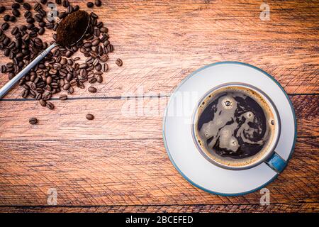 Piatto - caffè macinato e chicchi di caffè in tazza e piattino su tavole di legno Foto Stock