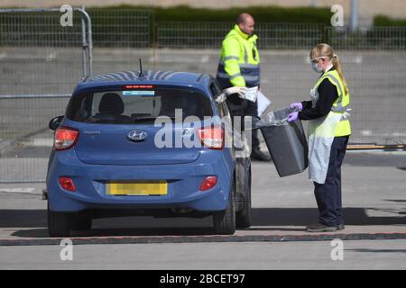 TARGA AUTO PIXEATED BY PA PICTURE DESK un lavoratore NHS mette un pacco in un contenitore etichettato 'solo kit di prova' presso un sito di test di coronavirus in un parcheggio vicino alla O2 a Greenwich, Londra, come il Regno Unito continua in blocco per contribuire a frenare la diffusione del coronavirus. Foto Stock