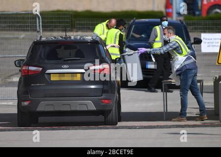 AUTO TARGA PIXEATED DA PA PICTURE DESK un lavoratore NHS mette un pacco in un bidone in un sito di test di coronavirus in un parcheggio vicino alla O2 a Greenwich, Londra, come il Regno Unito continua in blocco per contribuire a frenare la diffusione del coronavirus. Foto Stock