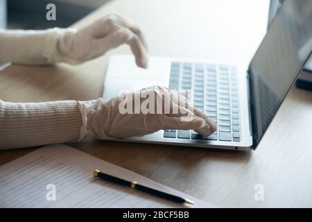 Giovane donna d'affari prudente che lavora sul computer con guanti. Foto Stock