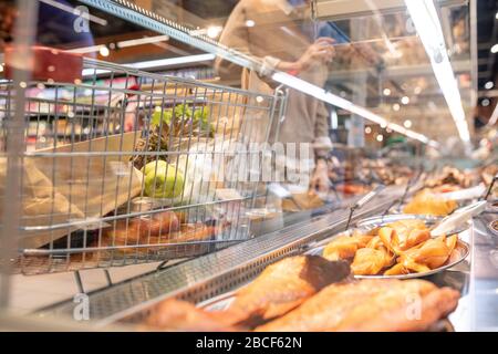 Pesce affumicato e altre specialità di pesce in grande esposizione nel supermercato e carrello con prodotti alimentari dietro il vetro Foto Stock