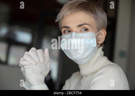 Donna attenta agli anni '30 che indossa una maschera medica e guanti protettivi. Foto Stock