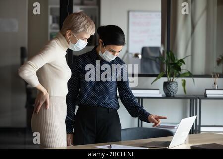 Ha messo a fuoco due donne in maschere protettive mediche che lavorano in ufficio. Foto Stock