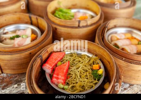 Dim Sum è cucina cinese su acciaio inossidabile tazza preparato piccole porzioni di cibo in piccoli cestini di bambù Foto Stock