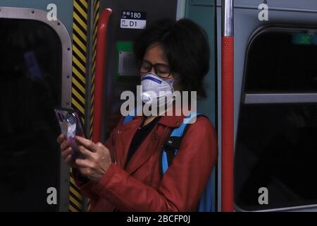 Hong Kong, CINA. 4th Apr, 2020. Donna fortemente protetta con facemask di grado industriale controllare il suo smartphone sulla MTR Train.April-4, 2020 Hong Kong.ZUMA/Liau Chung-ren credito: Liau Chung-ren/ZUMA Wire/Alamy Live News Foto Stock