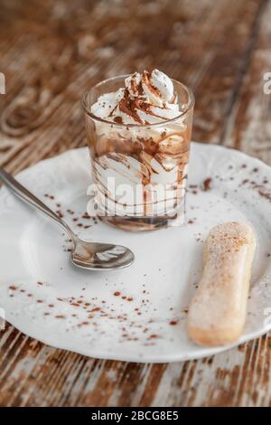 Tradizionale dessert italiano tiramisù in un bicchiere su tavolo rustico scuro Foto Stock