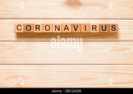 Coronavirus di parola con blocchi di legno, cubi su sfondo di legno. COVID-19. Concetto di autoisolamento. Quarantena del coronavirus. Lavoro da casa. Rimani a casa Foto Stock