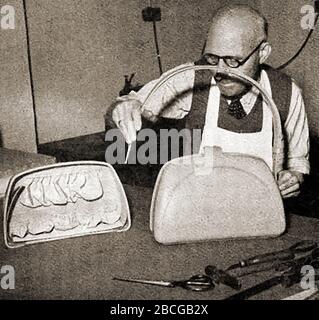 Una fotografia del 1920 di un operatore di pelle che fa una borsa a mano. Foto Stock