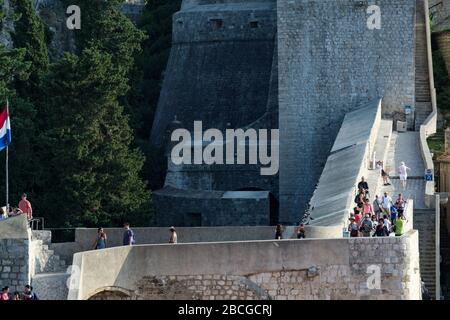 Turisti che camminano intorno alle mura della città all'esterno della città vecchia di Dubrovnik, Croazia Foto Stock