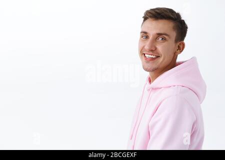 Ritratto ravvicinato di bel giovane studente maschio con capelli biondi, setole, in piedi nel profilo e girare a macchina fotografica con il sorriso beaming, guardando Foto Stock