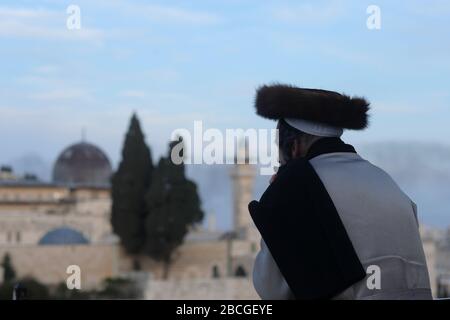 Un ebreo asidico che indossa uno shtreimel un cappello di pelliccia indossato da molti uomini ebrei Haredi sposati guarda alla moschea di al Aqsa un santuario islamico situato sul monte del Tempio noto ai musulmani come l'Haram esh-Sharif nella Città Vecchia Gerusalemme Est Israele Foto Stock