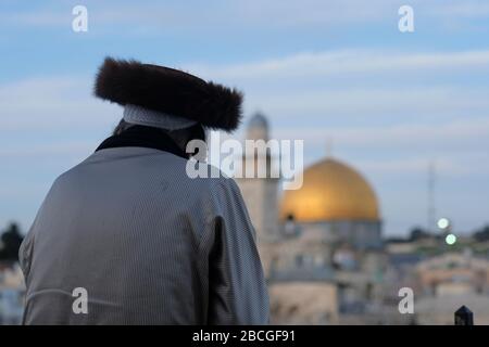 Un ebreo asidico che indossa uno shtreimel un cappello di pelliccia indossato da molti uomini ebrei Haredi sposati guarda alla cupola della roccia un santuario islamico situato sul monte del Tempio noto ai musulmani come l'Haram esh-Sharif nella Città Vecchia Gerusalemme Est Israele Foto Stock