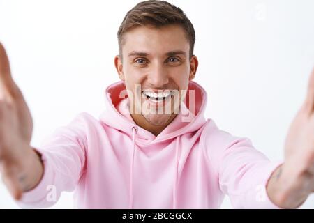 Primo piano ritratto di felice, amichevole biondo bello uomo videochat amici durante sociale-distansing covid19 pandemic, tenendo fotocamera entrambe le mani Foto Stock