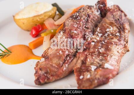 Filetto di maiale alla griglia con patate e verdure al forno. Foto Stock