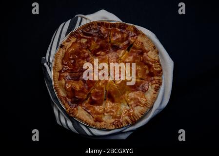 Torta di mele su sfondo nero avvolto in un panno per piatti visto dal concetto di cibo top-Harvest Foto Stock