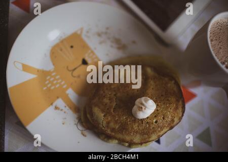 Il bambino mangia pancake con panna acida e cacao. Primo piano. Foto Stock