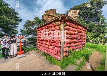 Isola di Enoshima, Giappone - 18 agosto 2019 : Wishes scritto su targhe Ema rosse a Musubi no Ki (due tronchi) Foto Stock