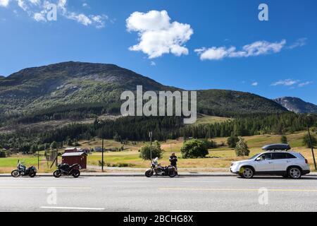 Tre moto e auto in piedi sulla strada di autostrada in montagna della Norvegia. Viaggi in Scandinavia in auto. Europa Foto Stock