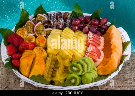 Frutta fresca sana in un cestino sulla tabella frutta a fette in un cestino kiwi ananas fragola. Foto Stock