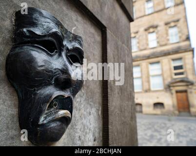 Maschera teatrale in bronzo rilievo con triste volto su High Street wellhead sul Royal Mile a Edimburgo, Scozia, Regno Unito, per indicare la tristezza della cancellazione del festival Edinburgh Fringe 2020. Foto Stock