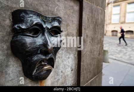 Maschera teatrale in bronzo rilievo con triste volto su High Street wellhead sul Royal Mile a Edimburgo, Scozia, Regno Unito, per indicare la tristezza della cancellazione del festival Edinburgh Fringe 2020. Foto Stock