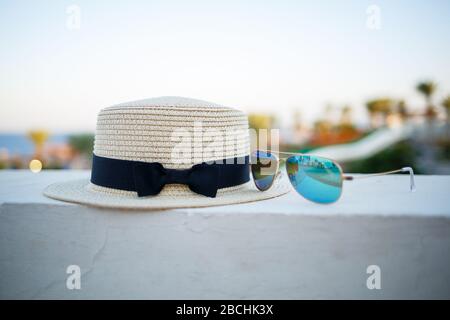 Cappello e occhiali estivi per donne si trovano sulla terrazza con vista sul mare Foto Stock