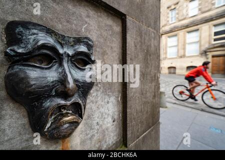 Maschera teatrale in bronzo rilievo con triste volto su High Street wellhead sul Royal Mile a Edimburgo, Scozia, Regno Unito, per indicare la tristezza della cancellazione del festival Edinburgh Fringe 2020. Foto Stock