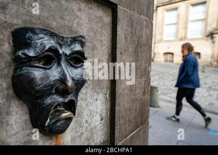 Maschera teatrale in bronzo rilievo con triste volto su High Street wellhead sul Royal Mile a Edimburgo, Scozia, Regno Unito, per indicare la tristezza della cancellazione del festival Edinburgh Fringe 2020. Foto Stock